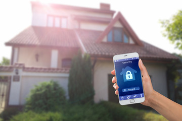 Smartphone with home security app in a hand on the building background