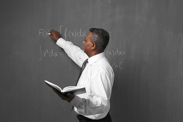 Canvas Print - Confident Indian teacher writing math formulas on blackboard