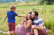© o_lypa - Child tickles his pregnant mother a blade of grass