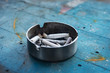 metal ashtray with cigarette butts on blue wooden table