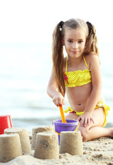 Canvas Print - Cute girl building sandcastle on beach