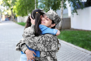 Mother in army uniform and daughter in the street