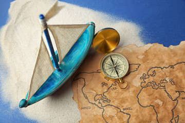 Wall Mural - Wooden boat, compass and old map on blue background. Columbus Day concept