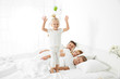 © Africa Studio - Cute little girl jumping on bed while her family is sleeping