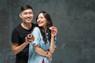 Young asian couple enjoy eating of sweet colorful donut