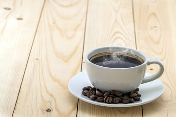 Wall Mural - White cup with black steaming coffee on plate with coffee beans