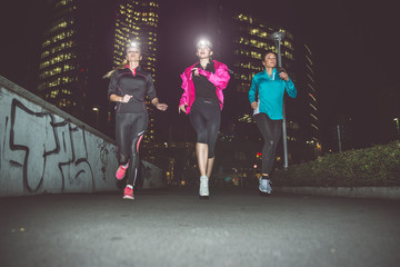 Three women running in the night in the city center