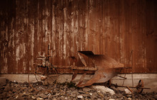 Rusty Old Horse Plow - A Closeup Of The Ancient Rural Farming Machine Made Of Rusting And Decaying Iron, Positioned In Front Of A Wooden Barn. A Western Style Background With Brown Color Tone.