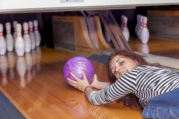 young woman sliding down a bowling alley