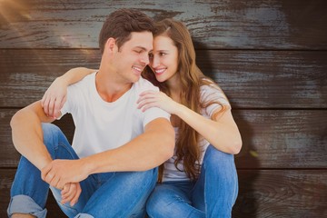 Poster - Composite image of young couple sitting on floor embracing