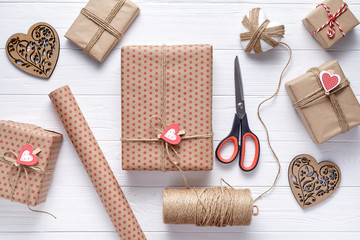 Wall Mural - Flat lay composition with gifts, scissors, wrapping paper and twine. Packaging of gifts on Valentine's Day, a birthday. White wooden background. Flat lay. Top view.