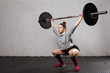 Woman athlete doing a overhead squat  with a barbell  in the  crossfit gym