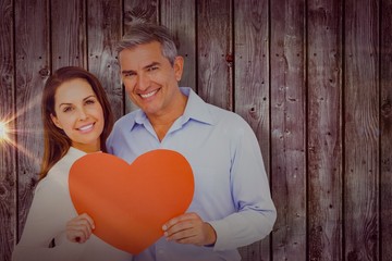 Canvas Print - Composite image of happy couple holding big heart shape paper