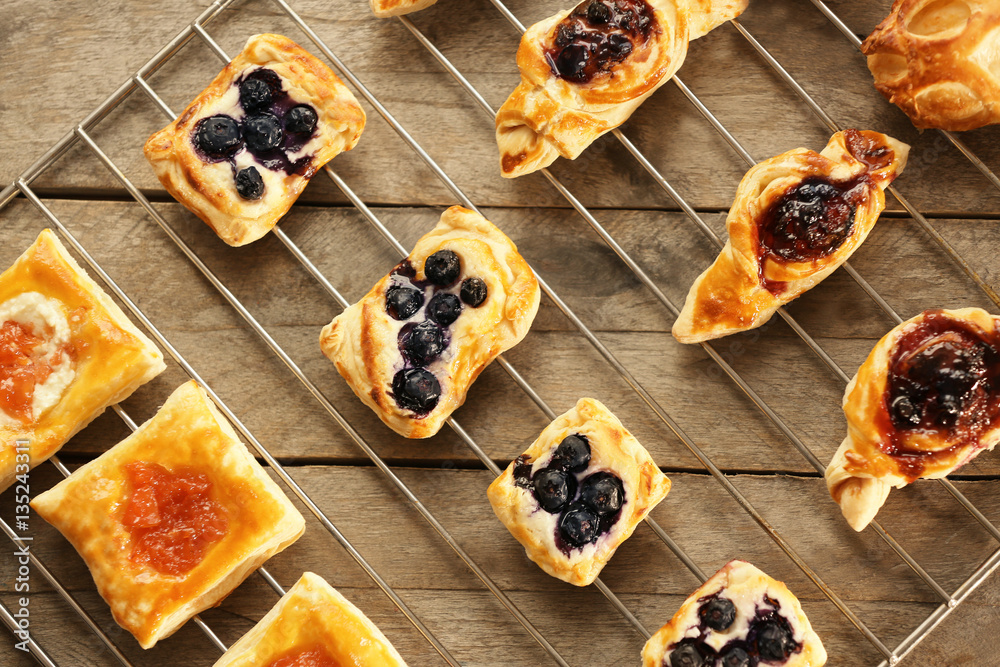 Sweet tasty pastries on baking grid against wooden background