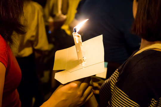 People holding candle vigil in darkness seeking hope, worship, prayer