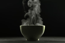 A Bowl Of Hot Food And Steam On Dark Background.