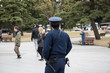 A japanese cop watching at the people can be seen in the picture. Few people and big trees can be seen in the image.
