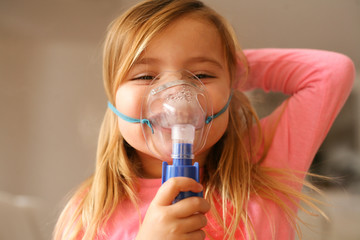 little girl using inhaler.