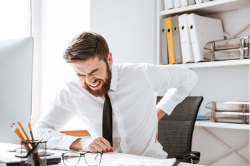 Businessman with painful feelings holding his back.