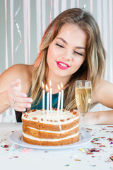 Wall Mural - Pretty girl looking at lit candles on birthday cake for celebrat