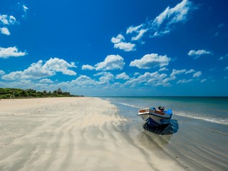 Isolated Boat on Amazing Beautiful scenic unspoiled white sand sandy beach with sand pattern and blue sky with white clouds near Pigeon Island in Trincomalee, Sri Lanka