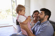 © Monkey Business - Parents Playing With Baby Daughter On Sofa At Home