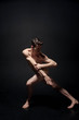 © zinkevych - Skilled young dancer stretching in the black studio