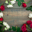 Floral round frame of red and wood roses isolated on wood background. Flat lay, top view.