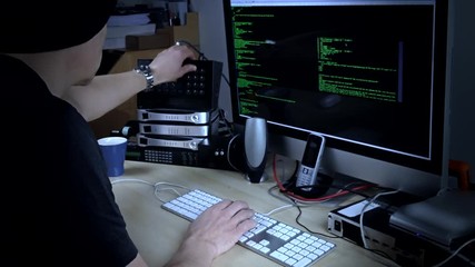 Hacker programmer at work on computer with streaming code on screen