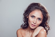 © kanashkin - Brunette girl with shiny wavy hair and beautiful make up posing at studio on grey background.