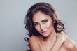 © kanashkin - Brunette girl with shiny wavy hair and beautiful make up posing at studio on grey background.