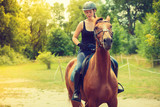 Fototapeta Konie - Jockey girl doing horse riding on countryside meadow