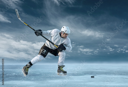 Fototapeta na szkło Ice hockey player in action outdoor around mountains