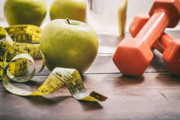 Green apples, dumbbells and measuring tape