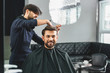 Happy guy getting haircut by hairdresser
