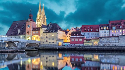 Fototapete - Historical Stone Bridge, tower and buildings in the evening, Regensburg, Germany  (static image with animated sky and water)
