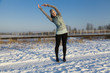 Woman in winter is stretching after jogging in the park