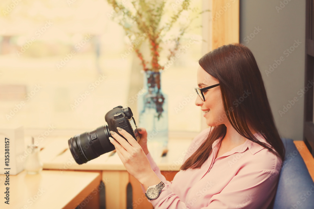 Beautiful young photographer with camera in cafe