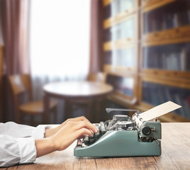 Wall Mural - Man working on retro typewriter at desk in library