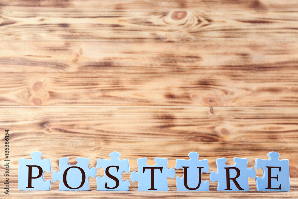 Blue puzzles with word POSTURE on light wooden background