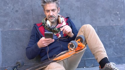 Wall Mural - Skateboarder sitting in urban area listening to music