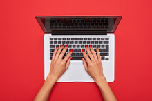 Woman Typing On A Laptop Keyboard On Red Flat Lay Background