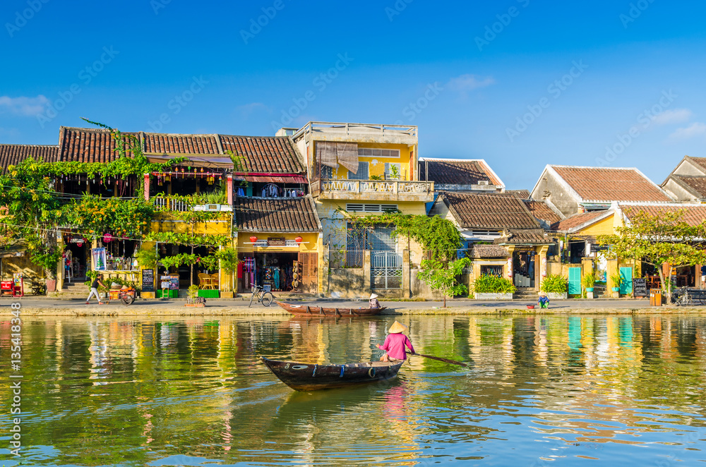 Woman crossing a river on a boat in Hoi An during mid day - obrazy, fototapety, plakaty 
