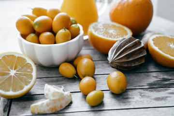 Wall Mural - Kumquat in a white bowl, oranges, lemons and fresh juice squeeze