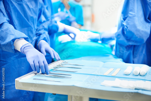 Cuadros en Lienzo Surgeon taking scissors from the table