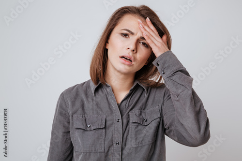 Fotografia Sick young woman with headache touching her head.