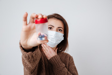 Wall Mural - Woman in sweater and medical mask holding tablets