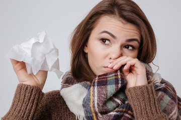 Wall Mural - Sick young lady with napkin over gray background.