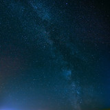 Fototapeta Niebo - Night Starry Sky Above Field And Yellow City Lights On Backgroun
