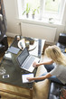 © Maskot - High angle view of teenage girl writing on book while using laptop at home